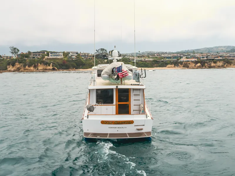 Slide: The Image of 1984 Vic Franck pilothouse yacht on ocean near coastal homes, American flag displayed. - 6