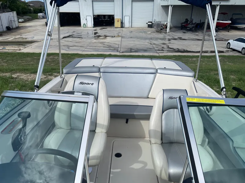 Slide: The Image of 2009 Sea Ray 175 Sport boat interior with seating and windshield, parked near a garage. - 11