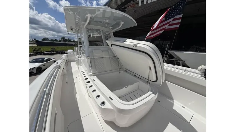 Slide: The Image of 2022 Invincible 33 Catamaran with open storage compartment, American flag, and clear sky background. - 11