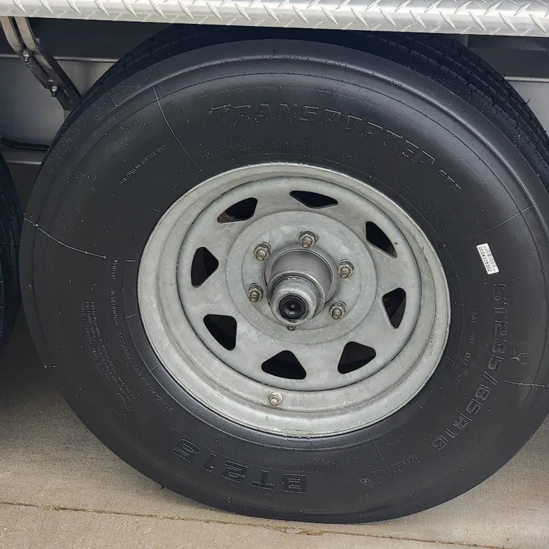 Slide: The Image of Trailer wheel of a 2022 Invincible 33 Catamaran, featuring a sturdy tire and metal rim. - 16