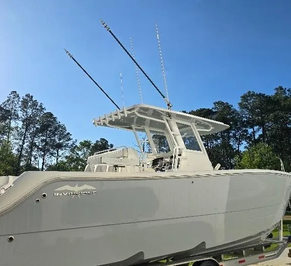 Slide: The Image of 2022 Invincible 33 Catamaran boat with fishing rods, parked outdoors under clear blue sky. - 17