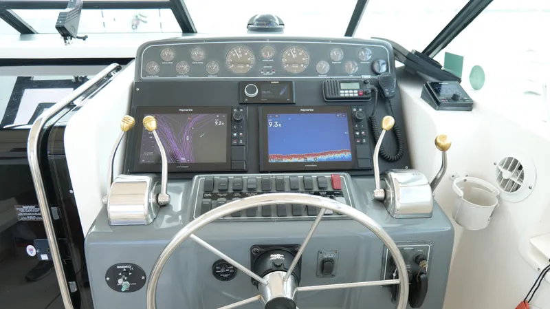 Slide: The Image of Control panel of a 2000 Tiara Yachts 3700 Open with navigation displays and steering wheel. - 19
