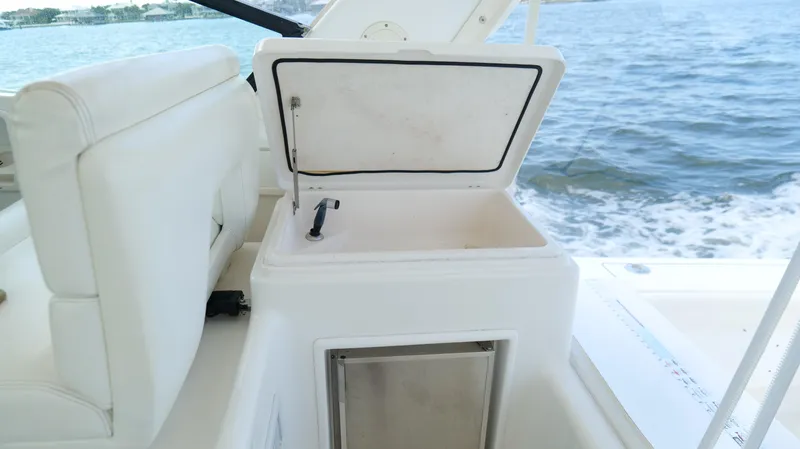 Slide: The Image of 2000 Tiara Yachts 3700 Open boat interior with open storage compartment, white seating, and ocean view. - 25