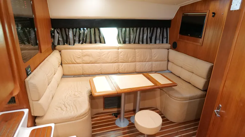 Slide: The Image of Interior of 2000 Tiara Yachts 3700 Open with beige seating and wooden table. - 30