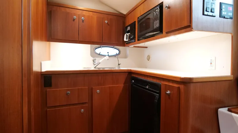 Slide: The Image of 2000 Tiara Yachts 3700 Open galley with wood cabinetry, microwave, and sink. - 34