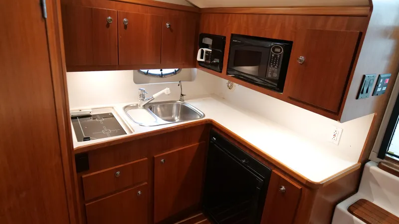 Slide: The Image of Compact kitchen in 2000 Tiara Yachts 3700 Open, featuring wood cabinets and modern appliances. - 35