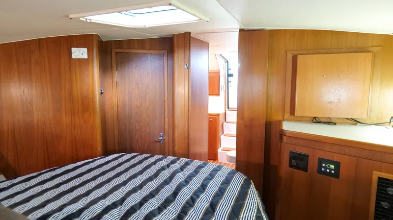 Slide: The Image of Interior cabin of 2000 Tiara Yachts 3700 Open, featuring wood paneling and striped bedding. - 39