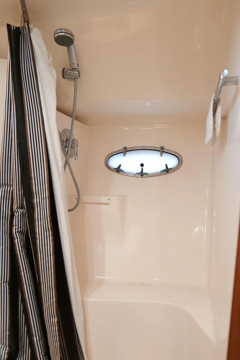 Slide: The Image of Shower area in 2000 Tiara Yachts 3700 Open, featuring striped curtain and porthole window. - 41