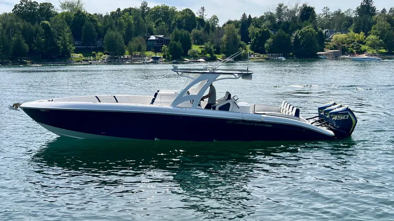 Slide: The Image of 2022 Midnight Express 37 Open boat on a serene lake with lush green shoreline. - 25