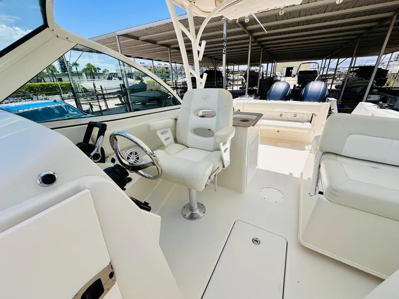 Slide: The Image of 2014 Sailfish 275 DC boat interior with white seating and steering wheel. - 14