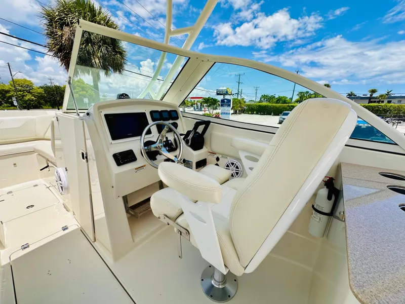 Slide: The Image of 2014 Sailfish 275 DC boat cockpit with steering wheel and seating under blue sky. - 15