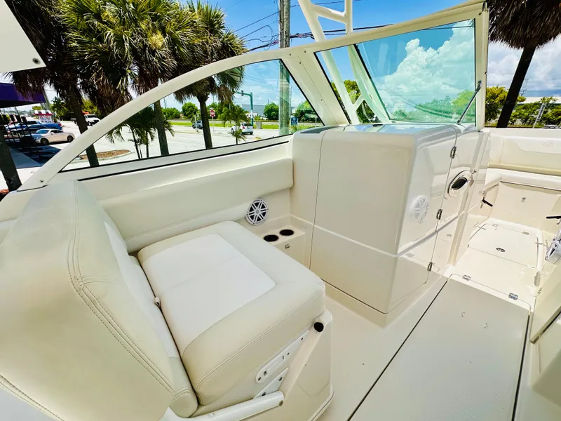 Slide: The Image of 2014 Sailfish 275 DC boat interior with white seating and clear windshield. - 17