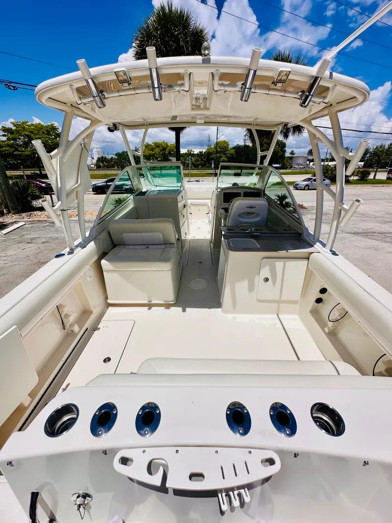 Slide: The Image of 2014 Sailfish 275 DC boat interior with seating and fishing rod holders under a clear sky. - 9