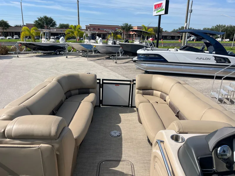 Slide: The Image of 2019 Regency 230 LE3 pontoon boat with beige seating, displayed at a dealership. - 12