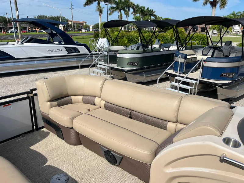 Slide: The Image of 2019 Regency 230 LE3 pontoon boat with beige seating, displayed alongside other boats. - 13