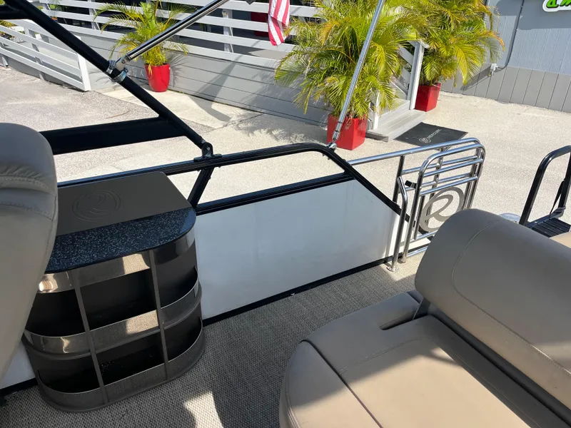 Slide: The Image of Interior of 2019 Regency 230 LE3 boat with seating and storage, docked near palm plants. - 19