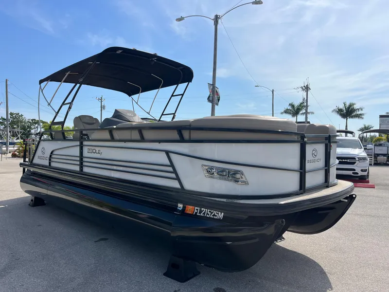 Slide: The Image of 2019 Regency 230 LE3 pontoon boat with canopy, parked on pavement under clear sky. - 3