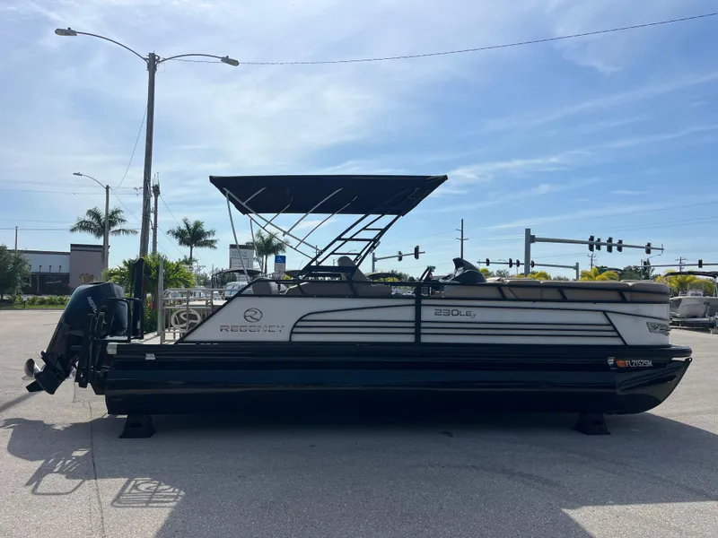 Slide: The Image of 2019 Regency 230 LE3 pontoon boat parked on a sunny street. - 4