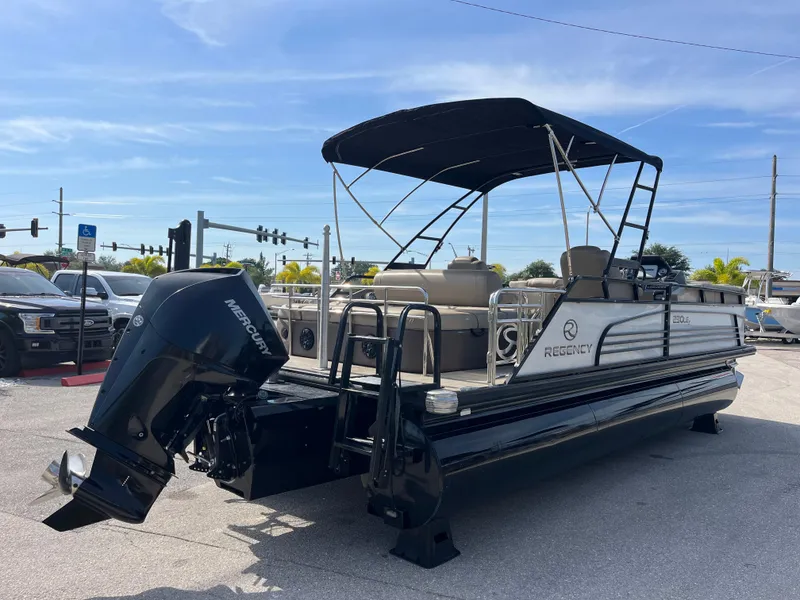 Slide: The Image of 2019 Regency 230 LE3 pontoon boat with Mercury outboard motor, parked outdoors. - 5