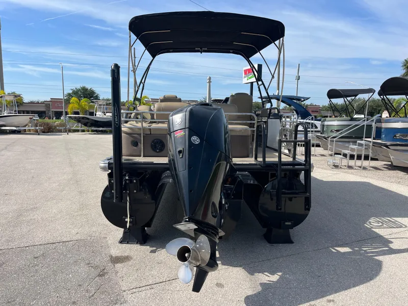 Slide: The Image of 2019 Regency 230 LE3 pontoon boat with outboard motor, parked outdoors under clear sky. - 6
