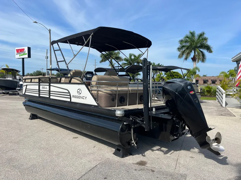 Slide: The Image of 2019 Regency 230 LE3 pontoon boat with canopy and outboard motor, parked outdoors. - 7