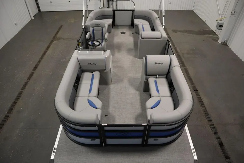 Slide: The Image of 2025 Bentley Pontoons 223 Bolt Tri-Toon interior with gray and blue seating in a showroom. - 11
