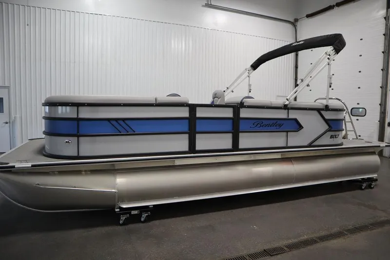 Slide: The Image of 2025 Bentley Pontoons 223 Bolt Tri-Toon in a showroom, featuring sleek design and blue accents. - 9