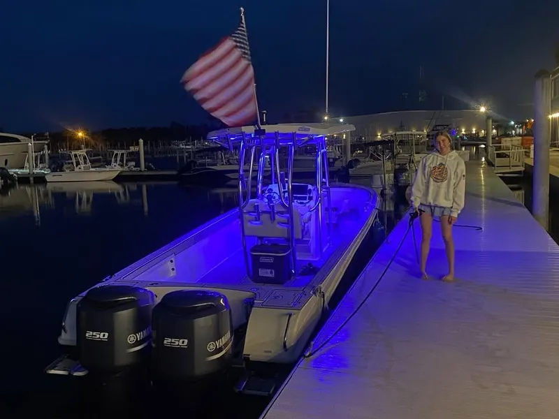 Slide: The Image of A Custom Shark Fin R321 boat docked at night, illuminated with blue lights. - 7