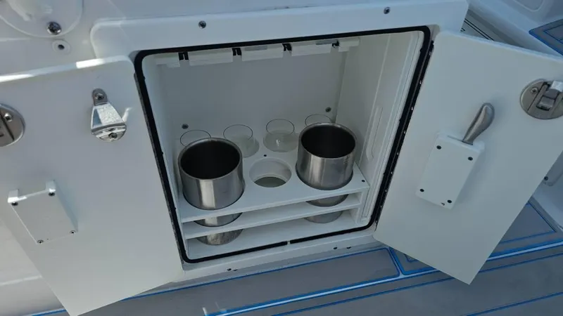 Slide: The Image of Open storage compartment on 2023 Sea Hunt Ultra 305 SE boat with drink holders. - 16