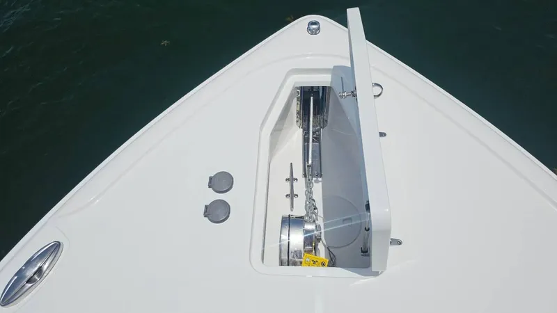 Slide: The Image of 2023 Sea Hunt Ultra 305 SE boat anchor compartment, open lid, on calm water. - 7