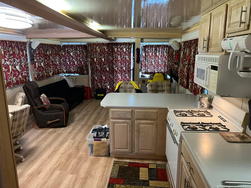 Slide: The Image of Interior of 1996 Fun Country houseboat with kitchen and living area, floral curtains, and wood flooring. - 12
