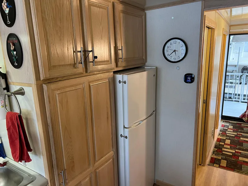 Slide: The Image of Kitchen area in a 1996 Fun Country houseboat with wooden cabinets and a white fridge. - 15