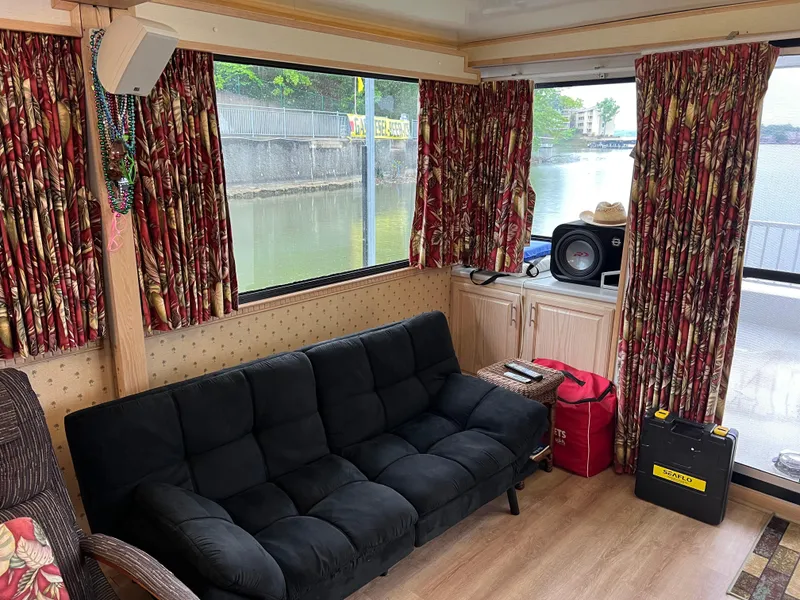 Slide: The Image of Interior of 1996 Fun Country houseboat with black sofa, floral curtains, and lake view. - 17