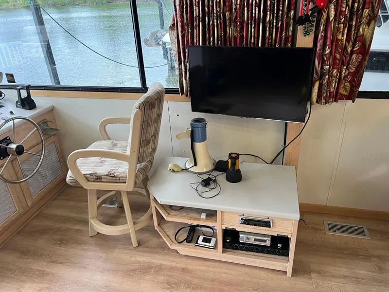 Slide: The Image of Interior of a 1996 Fun Country houseboat with steering wheel, chair, and entertainment setup. - 28