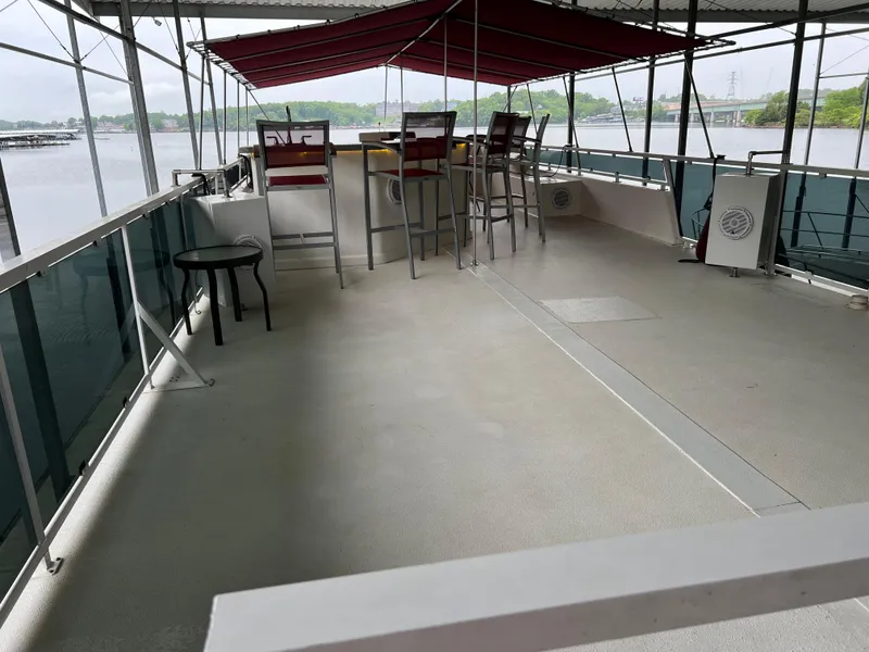 Slide: The Image of Houseboat deck with bar stools and canopy, overlooking a serene lake view. - 5