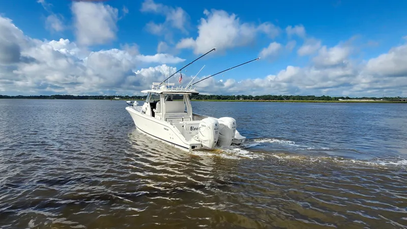 Slide: The Image of 2023 Pursuit S 358 Sport boat cruising on a calm river under a blue sky. - 11