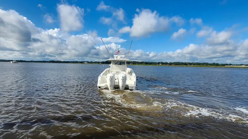 Slide: The Image of 2023 Pursuit S 358 Sport boat cruising on a calm lake under a blue sky. - 12