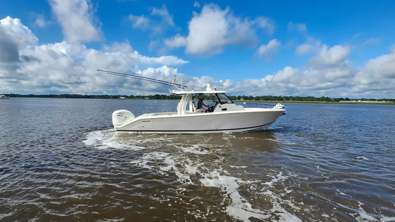 Slide: The Image of 2023 Pursuit S 358 Sport boat cruising on a calm lake under a blue sky. - 15