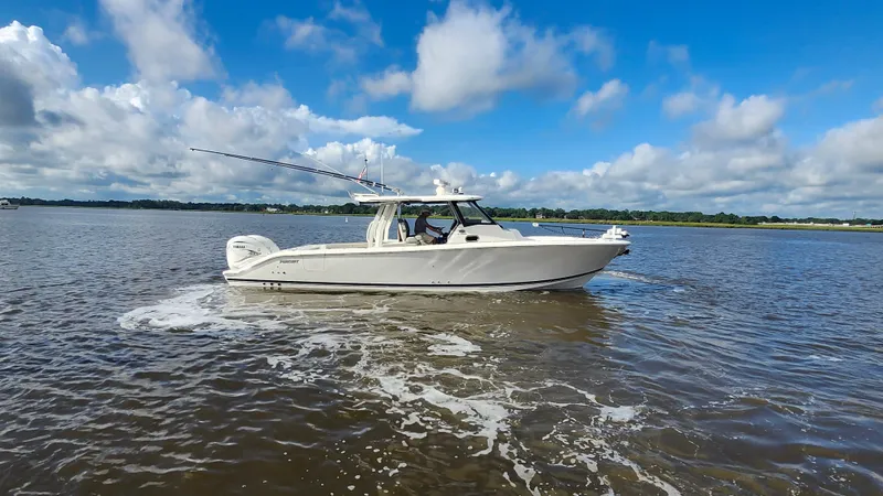 Slide: The Image of 2023 Pursuit S 358 Sport boat cruising on a calm lake under a blue sky. - 16