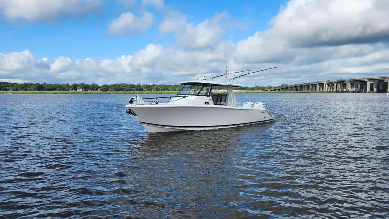 Slide: The Image of 2023 Pursuit S 358 Sport boat on calm water under a blue sky. - 2