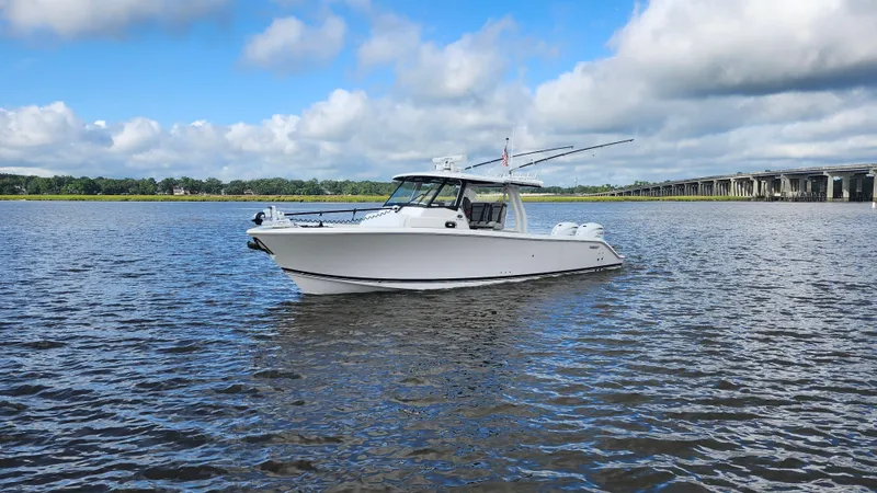 Slide: The Image of 2023 Pursuit S 358 Sport boat on calm water under a partly cloudy sky. - 3
