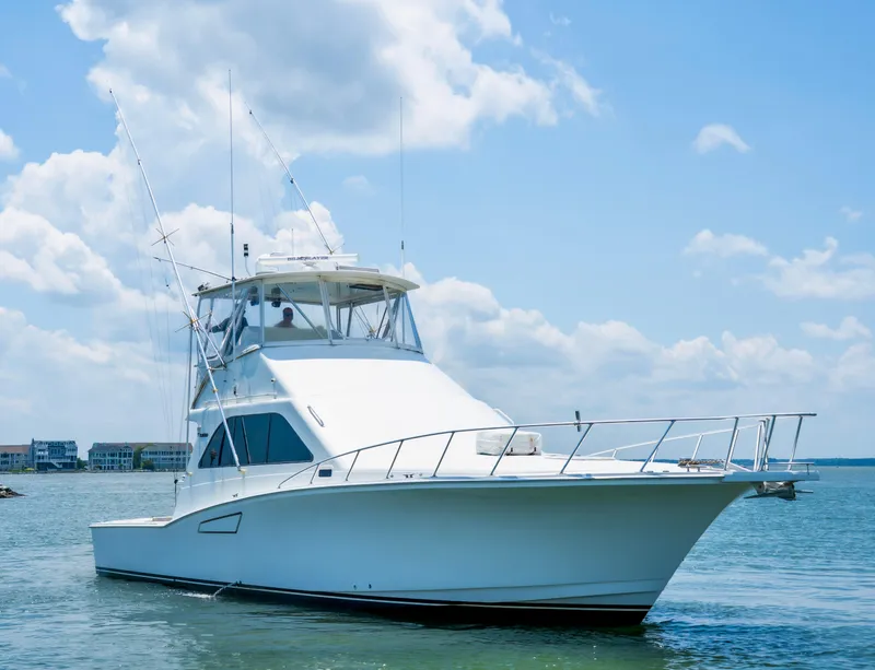 Slide: The Image of 2002 Cabo 47 Flybridge Sportfisher yacht on calm water under a clear blue sky. - 1