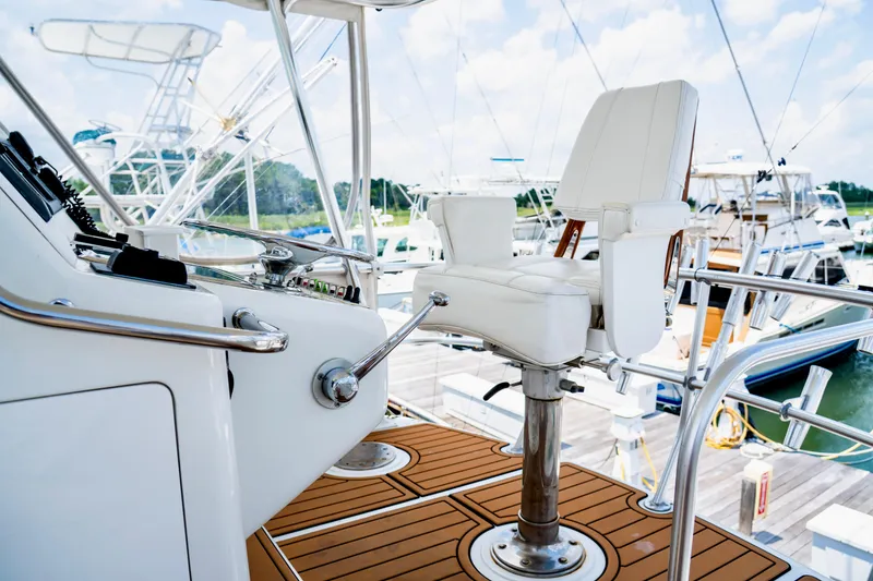 Slide: The Image of 2002 Cabo 47 Flybridge Sportfisher helm with white captain's chair and control panel. - 11