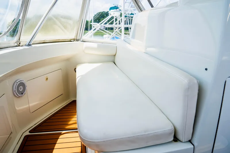 Slide: The Image of 2002 Cabo 47 Flybridge Sportfisher interior with white cushioned seating and wooden flooring. - 12