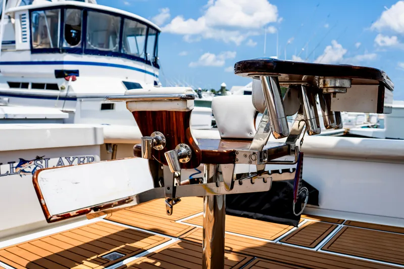 Slide: The Image of 2002 Cabo 47 Flybridge Sportfisher with fishing rod holders, docked under a clear blue sky. - 15