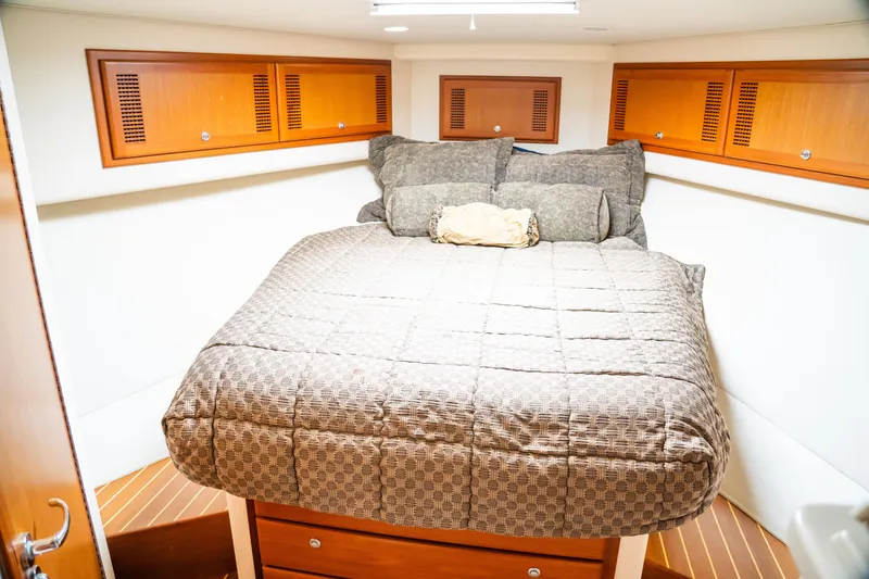 Slide: The Image of 2002 Cabo 47 Flybridge Sportfisher cabin with cozy bed and wooden storage cabinets. - 24