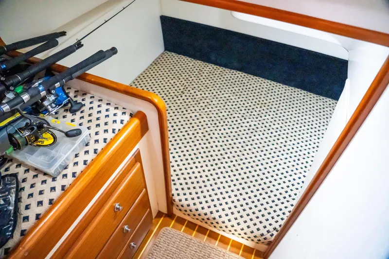 Slide: The Image of Interior of 2002 Cabo 47 Flybridge Sportfisher with fishing rods and patterned bedding. - 28
