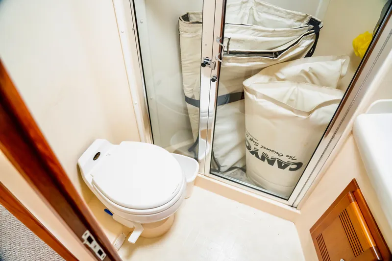 Slide: The Image of Bathroom on 2002 Cabo 47 Flybridge Sportfisher with toilet and storage bags. - 29
