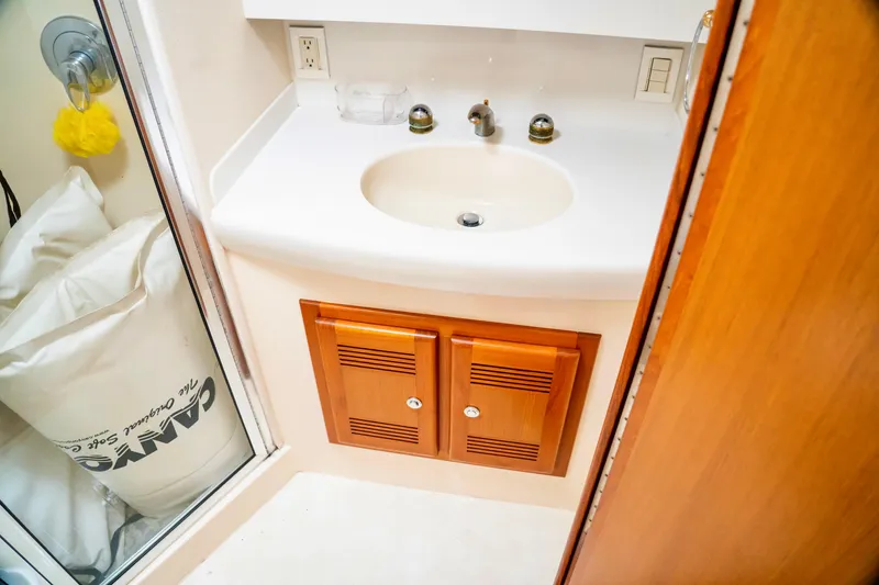 Slide: The Image of Bathroom sink area in 2002 Cabo 47 Flybridge Sportfisher yacht, featuring wooden cabinetry. - 30