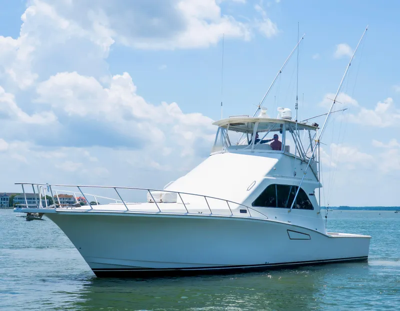 Slide: The Image of 2002 Cabo 47 Flybridge Sportfisher on calm water under a clear sky. - 4